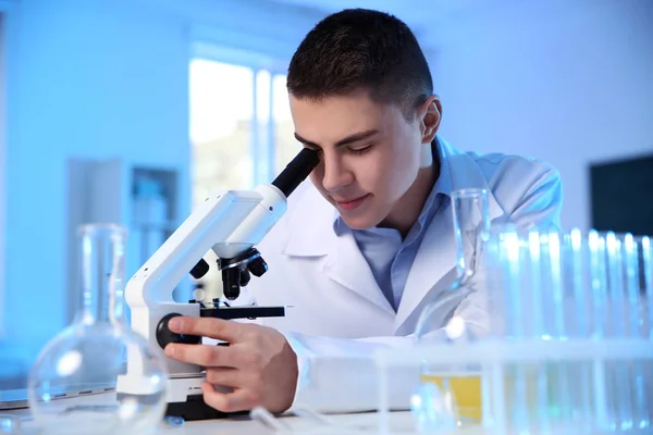 Científico masculino usando microscopio moderno en laboratorio de química — Foto de Stock