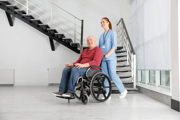 Verpleegkundige assisteren Senior man in rolstoel in het ziekenhuis — Stockfoto