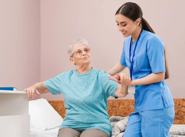 Verpleegkundige bijstaan Senior vrouw op bed in ziekenhuis Ward — Stockfoto