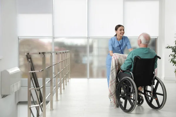 Verpleegkundige voor senior man in rolstoel met Plaid in het ziekenhuis. Medische hulp — Stockfoto