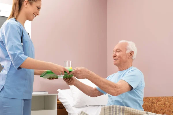 Νοσοκόμα δίνοντας δίσκο με φαγητό σε ανώτερο ασθενή στο νοσοκομειακό θάλαμο. Ιατρική βοήθεια — Φωτογραφία Αρχείου