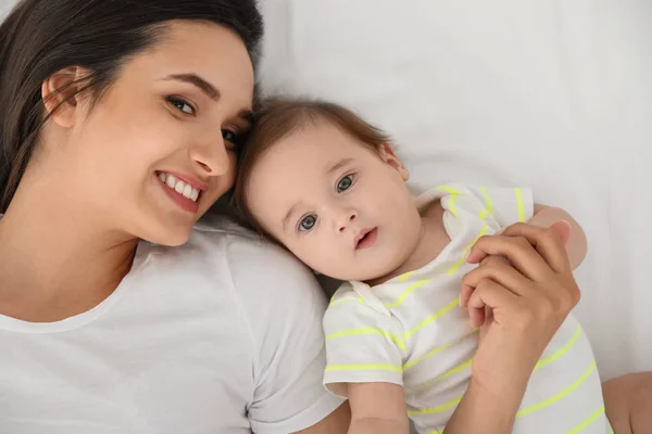 Portrait of mother with her cute baby lying on bed, top view — Stock Photo, Image