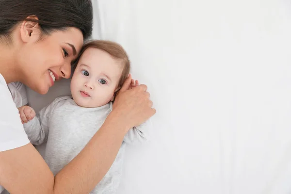 Retrato de la madre con su lindo bebé acostado en la cama, vista superior. Espacio para texto — Foto de Stock