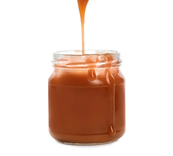 Sabrosa salsa de caramelo vertiendo en frasco aislado en blanco — Foto de Stock