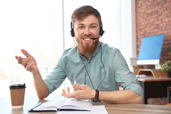 Young man with headset looking at camera and using video chat in home office — 스톡 사진