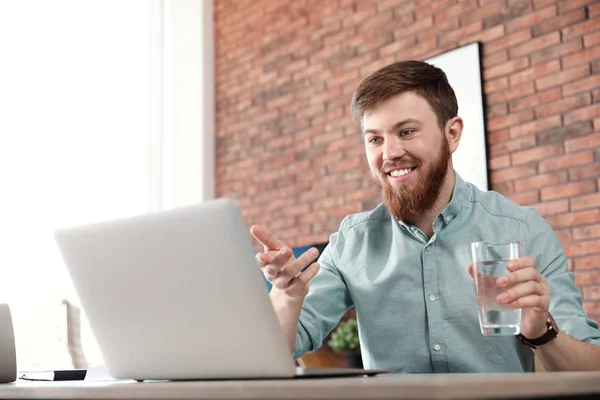 Young man using video chat on laptop in home office — 스톡 사진