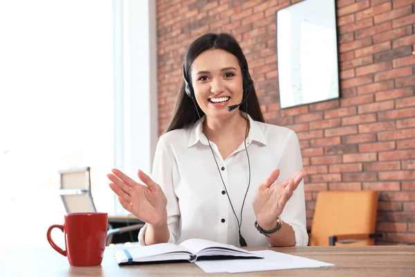 Jonge vrouw met headset kijken naar camera en het gebruik van video-chat in het kantoor aan huis — Stockfoto