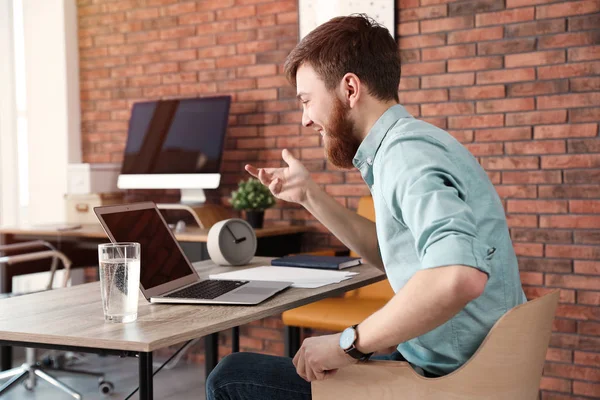 Hombre joven que utiliza el chat de vídeo en el ordenador portátil en la oficina. Espacio para texto —  Fotos de Stock