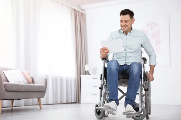 Szczęśliwy człowiek z tabletem siedzi na wózku inwalidzkim w domu — Zdjęcie stockowe