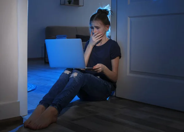Verängstigtes Teenager-Mädchen mit Laptop auf dem Boden in dunklen Raum. Gefahr des Internets — Stockfoto