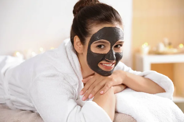 Wanita cantik dengan topeng hitam di wajah santai di spa salon — Stok Foto
