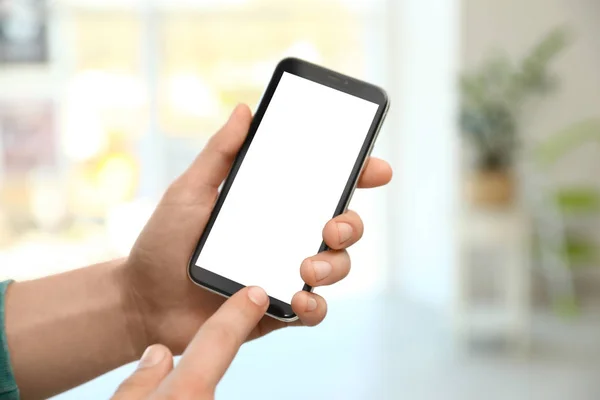 Homme tenant smartphone avec écran blanc à l'intérieur, gros plan des mains. Espace pour le texte — Photo