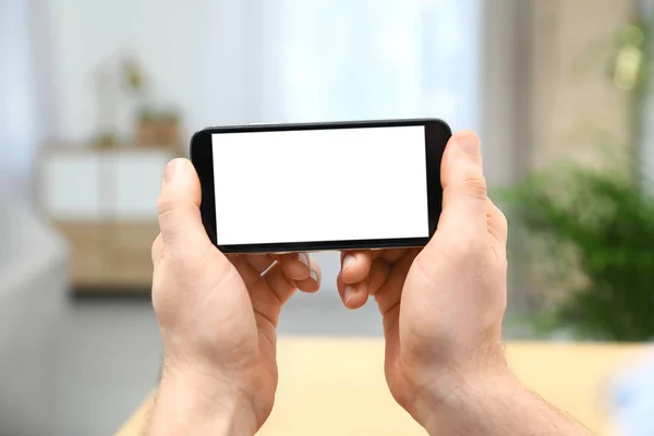 Mann hält Smartphone mit leerem Bildschirm drinnen, Nahaufnahme der Hände. Raum für Text — Stockfoto