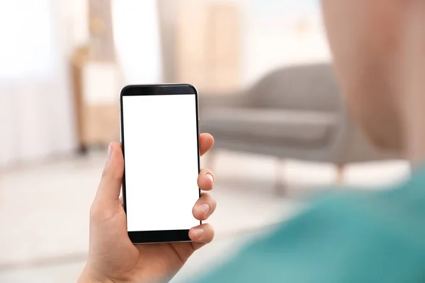 Hombre sosteniendo teléfono inteligente con pantalla en blanco en el interior, primer plano de la mano. Espacio para texto —  Fotos de Stock