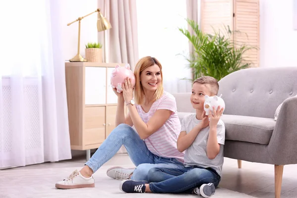Mor och son med piggy Banks hemma — Stockfoto
