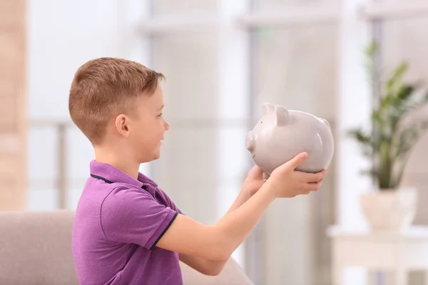 Kleine jongen met Piggy Bank thuis — Stockfoto