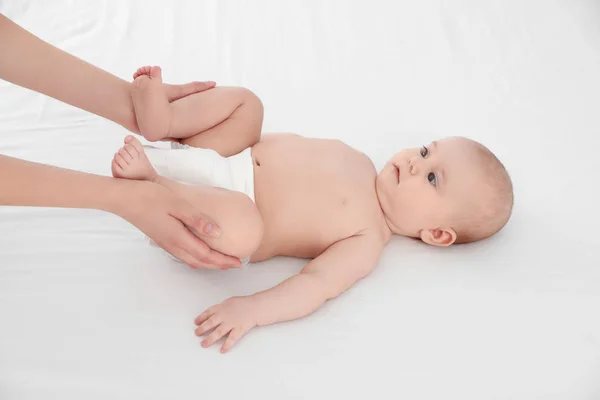 Mor och hennes söta barn på vit säng. Babymassage och övningar — Stockfoto