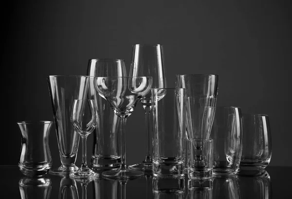 Óculos vazios para diferentes bebidas no fundo escuro — Fotografia de Stock