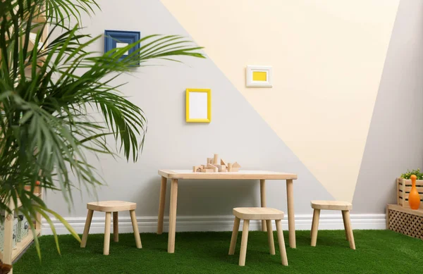 Stylish playroom interior with table, stools and green carpet — Stock Photo, Image