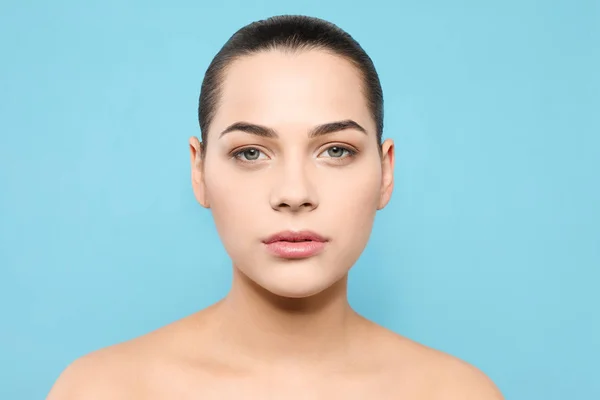 Portrait de jeune femme avec beau visage et maquillage naturel sur fond de couleur — Photo