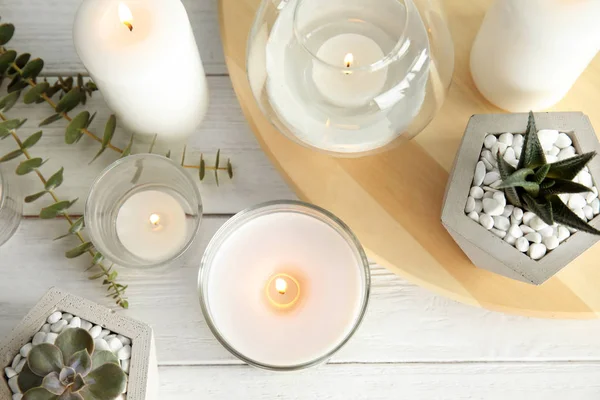 Плоская композиция с горящими ароматическими свечами и растениями на деревянном столе — стоковое фото