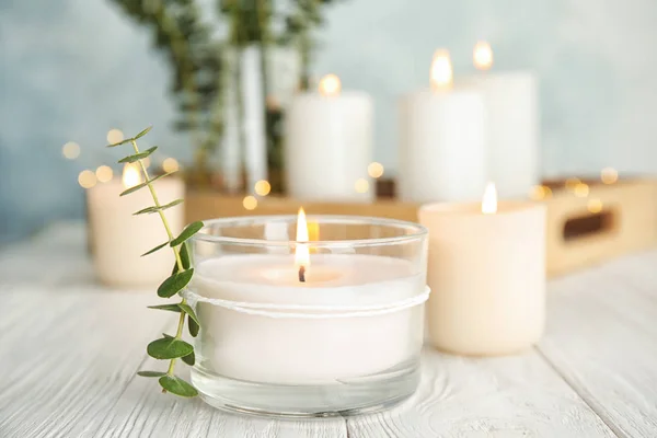 Горящие ароматические свечи и ветви эвкалипта на столе — стоковое фото