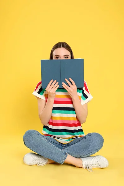 Молода жінка читає книгу на кольоровому фоні, простір для тексту — стокове фото