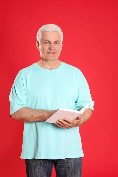 Senior Mann liest Buch auf farbigem Hintergrund — Stockfoto