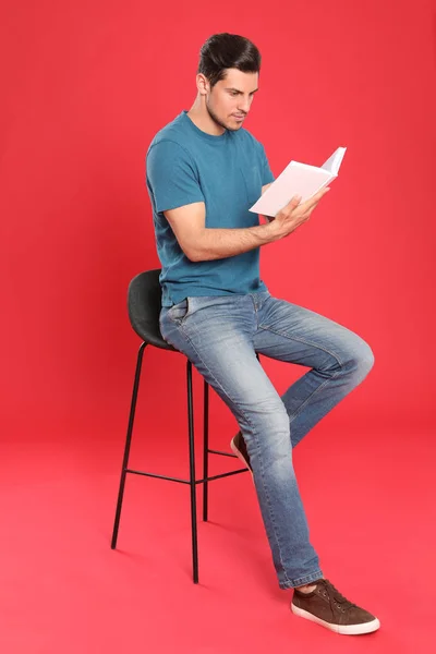 Hombre guapo leyendo libro sobre fondo de color — Foto de Stock