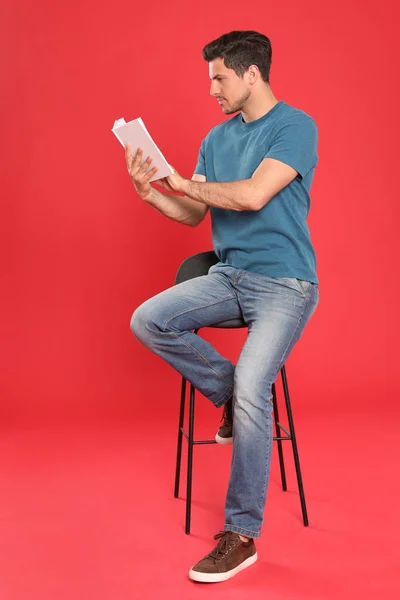 Schöner Mann liest Buch auf farbigem Hintergrund — Stockfoto