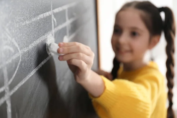 Kleines Mädchen schreibt Noten auf Schultafel im Klassenzimmer, Nahaufnahme Stockbild