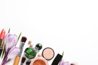 Beyaz arka planda farklı makyaj ürünleri ve çiçekler, üst görünüm
