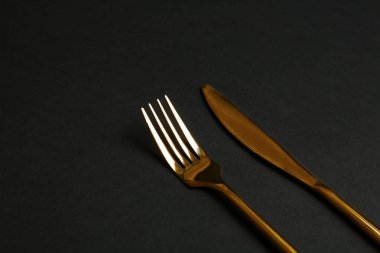 Siyah arka planda altın çatal ve bıçak. Metin alanı