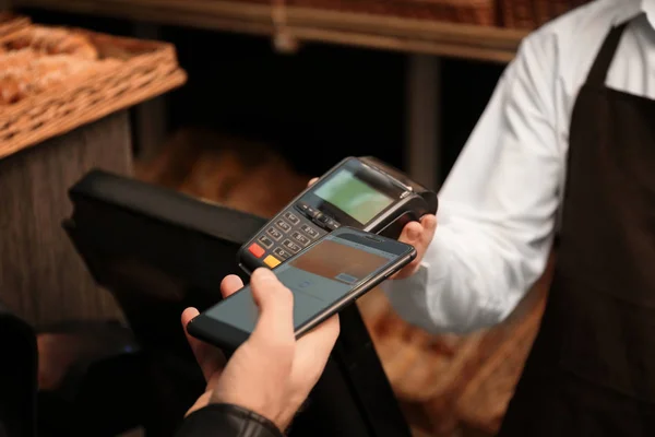 Hombre con smartphone usando terminal de pago en tienda, primer plano — Foto de Stock