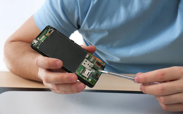 Técnico reparación de teléfonos inteligentes rotos en la mesa, primer plano —  Fotos de Stock