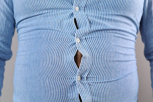 Overweight man with large belly in tight shirt , closeup
