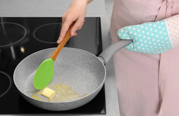 Mujer revolviendo mantequilla en la sartén en la estufa eléctrica, primer plano —  Fotos de Stock