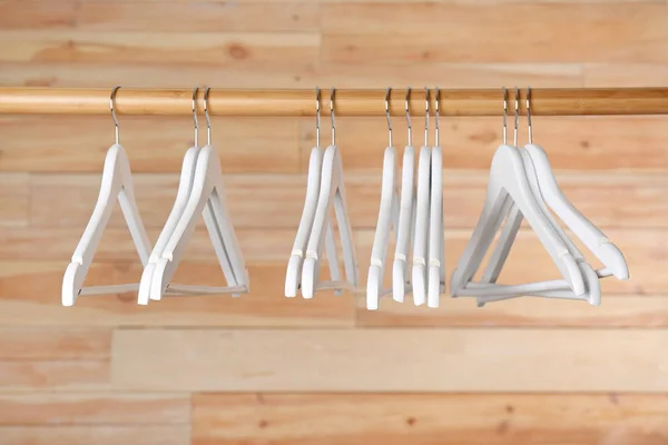 Rack with clothes hangers on wooden background — Stock Photo, Image