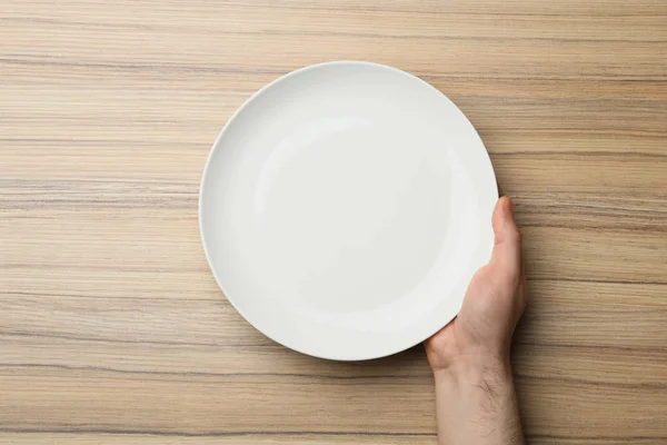 Homme avec plaque vide à la table en bois, vue de dessus — Photo