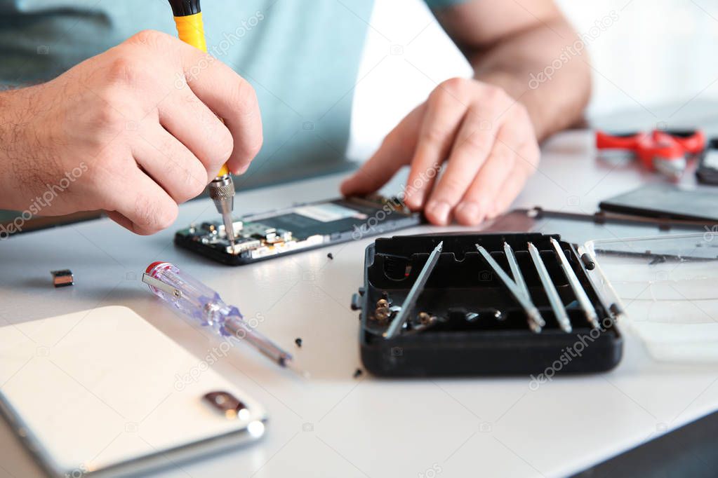 Technician repairing mobile phone at table, closeup