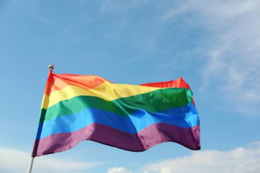 Parlak gökkuşağı gay bayrağı mavi gökyüzüne karşı çırpınan. Lgbt topluluğu