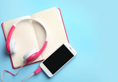 Modern kulaklıklar, telefon ve açık Notebook renkli arka plan, düz yatıyordu. Metin alanı