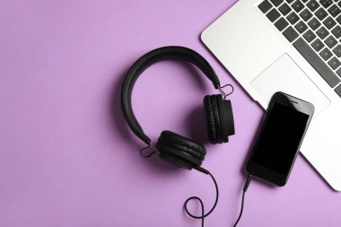 Modern kulaklıklar, telefon ve dizüstü renkli arka plan, düz yatıyordu. Metin alanı
