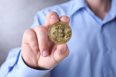 Renk arkaplanında altın bitcoin tutan adam, yakın plan