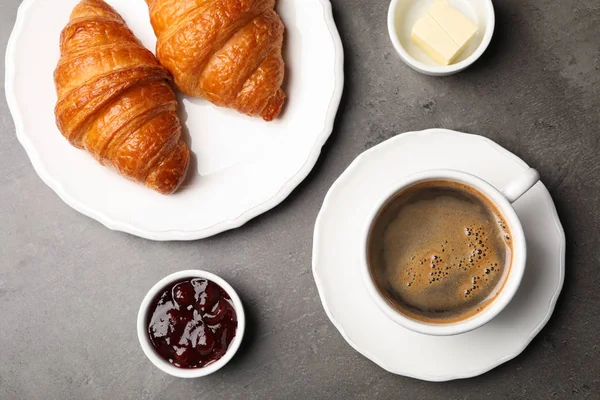 Composizione flat lay con tazza di caffè e croissant su fondo grigio — Foto Stock