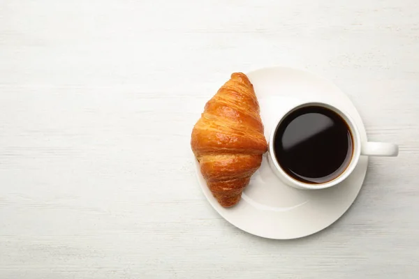 Teller mit Tasse Kaffee und Croissant auf weißem Holzgrund, flach gelegt. Raum für Text — Stockfoto
