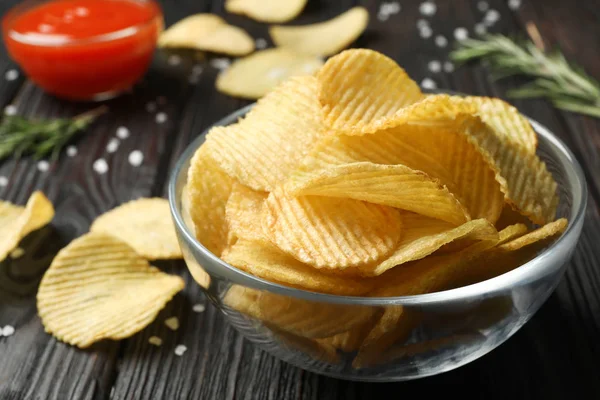 Bowl of potato chips on wooden table, closeup. Space for text