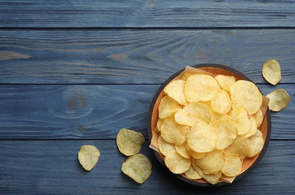 Kom en aardappelchips op houten tafel, bovenaanzicht. Ruimte voor tekst — Stockfoto