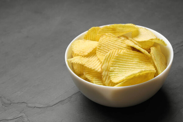 Чашка картофельных чипсов на сером столе. Пространство для текста
