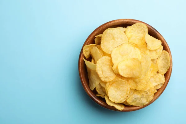 Heerlijke knapperige aardappelchips in kom op kleur achtergrond, bovenaanzicht met ruimte voor tekst — Stockfoto